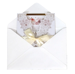Elegant white laser-cut wedding invitation with floral insert and beige satin bow decor