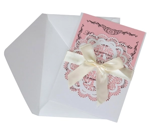 Detail of laser-cut white wedding invitation set with pink insert card and satin bow