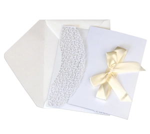 Detail of laser-cut floral invitation cover with champagne satin ribbon and white envelope