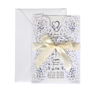 Elegant laser cut white wedding invitation set with silk ribbon and matching envelope