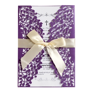 Detail of laser-cut purple wedding invitation with white ribbon and ornate leaf patterns