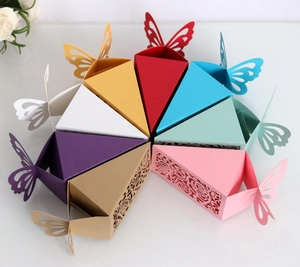 Macro detail of laser-cut rose patterns and butterfly top on paper wedding favor boxes