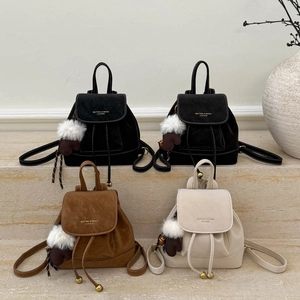 Minimalist mini leather backpacks in black and caramel colors on a stone pedestal