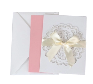 Detail of laser-cut floral lace wedding invitation with white ribbon and pink insert