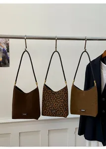 Three leopard print and matte suede tote bags hanging on a rack for fashion display