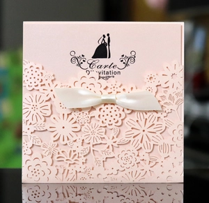 Détail de l'invitation de mariage en dentelle découpée au laser avec nœud de satin blanc