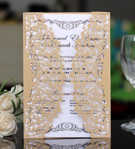 Detail of laser-cut gold leaf wedding invitation with white insert on reflective surface
