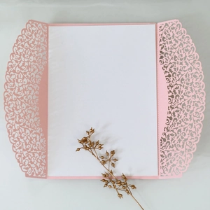 Detailed close-up of laser-cut floral pattern on elegant pink wedding invitation sleeve