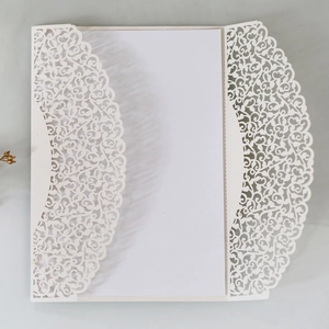 Macro shot of laser-cut white wedding invitation with elegant vine patterns and insert
