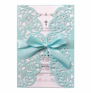 Close-up of light blue laser-cut wedding invitation with elegant satin ribbon bow