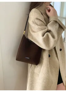 Detail of a brown suede hobo bag with a 'NO FILTER' leather label and golden metal buckle