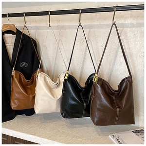 Détail de sacs seaux en quatre couleurs avec coutures apparentes et ferrures dorées