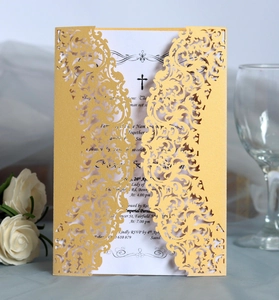 Detail of laser-cut gold lace wedding invitation with cross emblem and white insert card