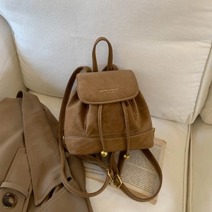 Close-up of brown textured leather mini backpack with drawstring and gold metal details