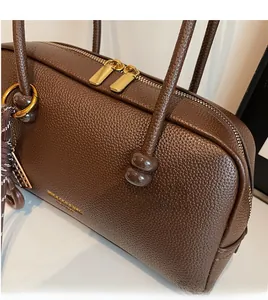 Close-up of pebble leather texture and gold-tone zippers on a brown bowling bag