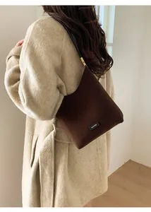 Detail of a vintage dark brown suede tote bag featuring a stitched 'NO FILTER' brand patch
