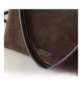 Dettaglio del secchiello in pelle scamosciata marrone scuro con manico e placca logo