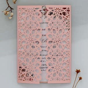 Macro shot of laser cut floral wedding invitation with pink cover and floral inner card