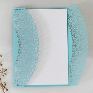 Macro detail of laser-cut lace floral pattern on light blue pearlescent wedding invitation