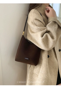 Detail of brown suede shoulder bag featuring NO FILTER leather label and gold hardware