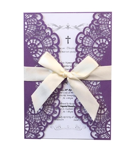 Detail of laser-cut floral pattern on purple wedding invitation with white satin bow