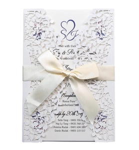 Elegant white laser-cut wedding invitation with hollow leaf pattern and satin bow decoration