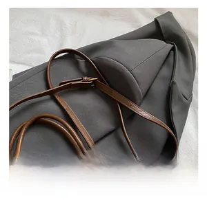 Detail of adjustable metal buckle and shoulder strap on brown suede bucket bag