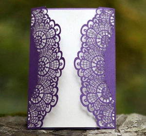 Detail einer lila lasergeschnittenen Hochzeitseinladung mit Spitzenmuster auf Holz