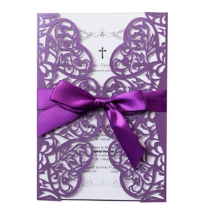 Detail of laser-cut purple wedding invitation with white insert and satin ribbon bow