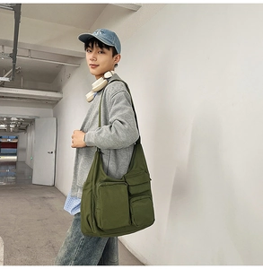 Detail of dark green canvas tote bag with multi-pocket utility design and wide strap
