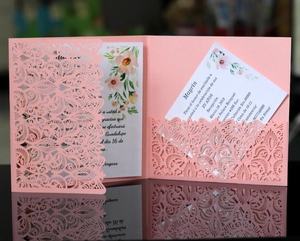 Detail of pink laser-cut invitation sleeve with floral insert on a reflective background