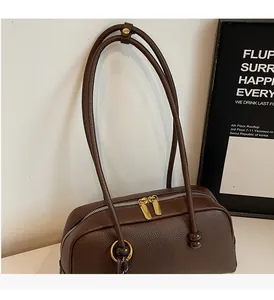 Detailed close-up of brown litchi leather texture and golden metal zipper of the bowling bag