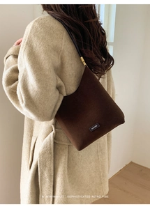 Detail of dark brown suede shoulder bag with NOFILTER label and golden metal hardware