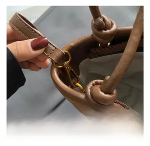 Detail showing the bronze spring hook and leather knot on the brown bucket bag