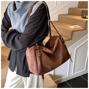 Close-up of brown suede shoulder bag featuring a refined golden buckle and leather strap
