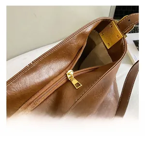 Détail de la fermeture éclair dorée et des finitions sur le sac seau en cuir marron foncé