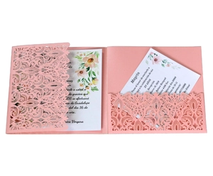 Detail of pink laser-cut wedding invitation with intricate hollow wave pattern and floral card