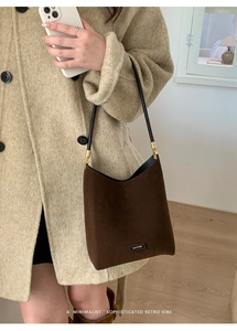 Detail of dark brown suede shoulder bag featuring a gold hardware and NO FILTER plaque