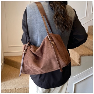 Brown suede shoulder bag on model showing large capacity and natural drape on stairs