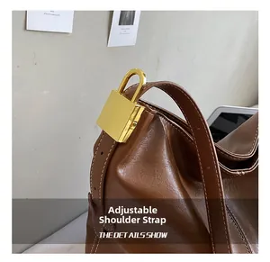 Détail du sac en cuir marron avec bandoulière réglable et boucle en métal doré