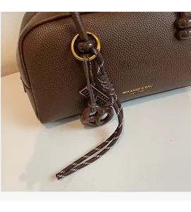 Detailed macro view of dark brown litchi grain leather bag with woven cord accessory