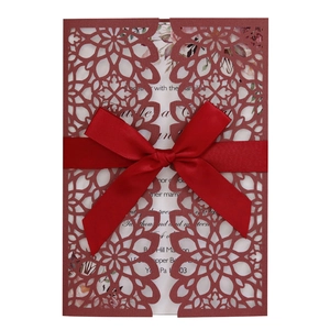 Laser-cut red wedding invitation with white floral insert and a decorative silk ribbon bow