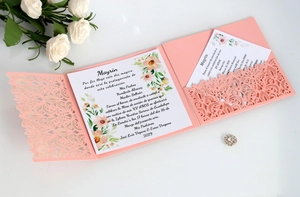 Close-up of laser-cut lace floral pattern on light pink wedding invitation card set