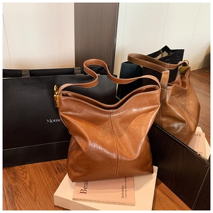 Détail d'un sac cabas en cuir caramel avec texture vintage et boucle dorée ajustable