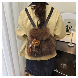 Detailansicht eines braunen Kunstfell Rucksacks mit niedlichem Monsteranhänger und Trägern