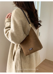 Detailed side view of a brown suede hobo bag with a black NO FILTER label and thin strap