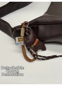 Close-up of a brown leather bag with a detachable puppy charm and printed fabric tag