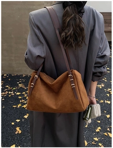 Detail of suede hobo bag in dark caramel brown with adjustable leather strap and gold buckle