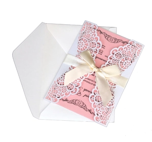 Detail der lasergeschnittenen Hochzeitseinladung mit rosa Inlay und cremefarbener Schleife