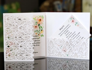 Detailed laser-cut wedding invitation with white floral lace cover and pink floral insert
